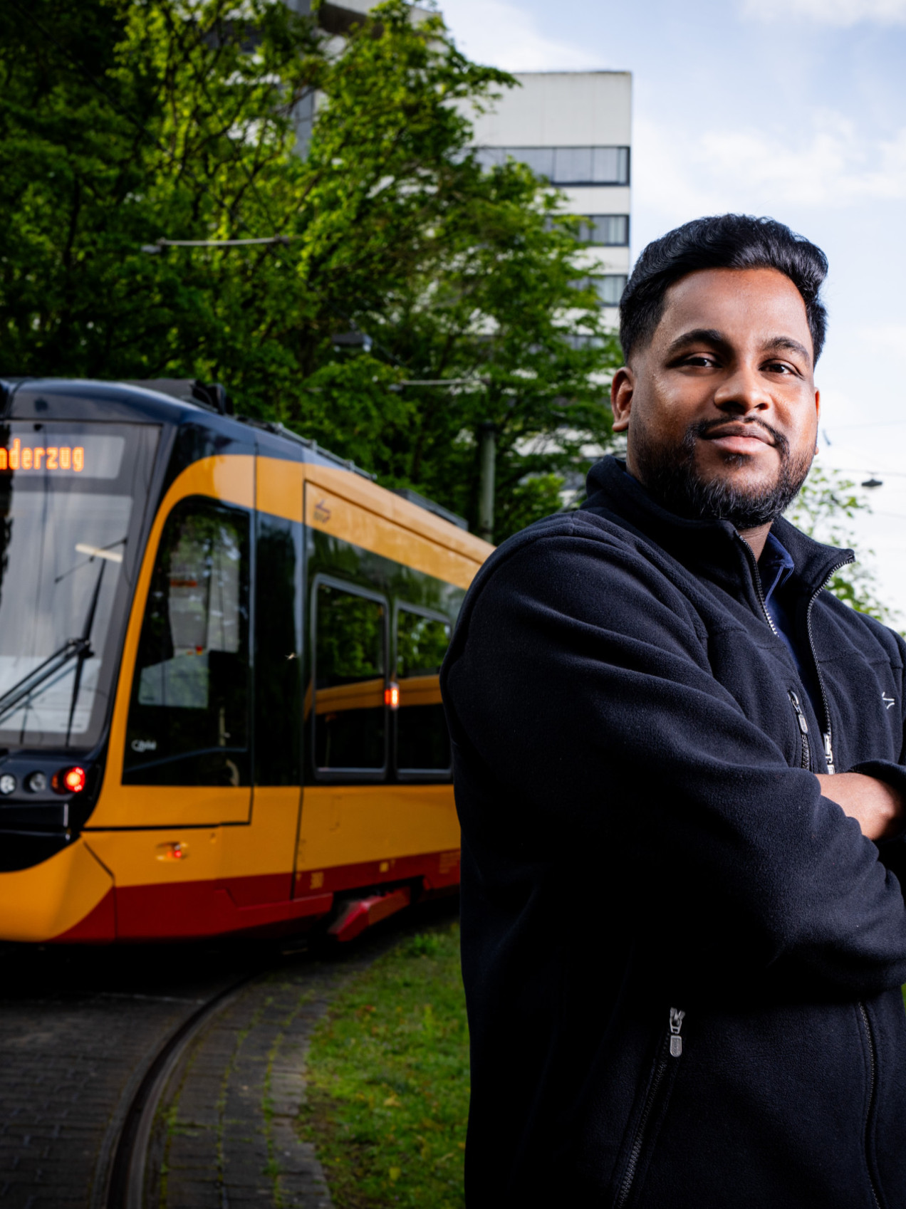 Ein Straßenbahnfahrer steht im freien vor einer Bahn.
